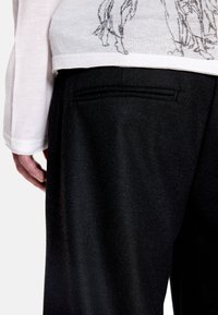 Μαύρο ραμμένο παντελόνι με υφή υφάσματος, με μία πίσω τσέπη και λείο ζωνάρι, συνδυασμένο με λευκό μακρυμάνικο τοπ.