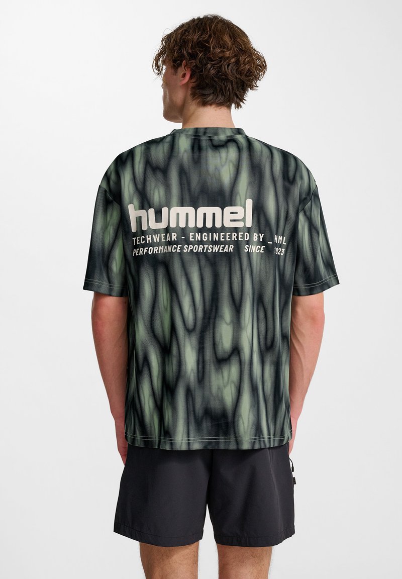 Mörkgrön och svart mönstrad t-shirt med "hummel"-logotyp på baksidan. Tillverkad av lätt material med avslappnad passform och korta ärmar.