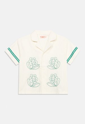 Chemise crème à manches courtes avec quatre fleurs vertes souriantes dessinées et deux rayures vertes sur chaque manche.