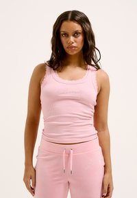 Top in cotone rosa chiaro a costine con bordo in pizzo e dettagli glitterati in scritta, abbinato a pantaloni della tuta rosa coordinati con vita regolabile tramite cordoncino.