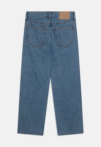 Blå denim vidbenade jeans med hög midja, typisk fem-fickorsdesign och en brun läderlapp på baksidan.