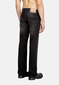 Črne jeans hlače s ravnim krojem, vidnimi šivi in značilno oznako na zadnjem žepu. Imajo dve zadnji žepek.