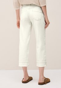 Vita denim croppade jeans med rullade fållar, två bakfickor och en mjuk textur, tillsammans med bruna slip-on skor.