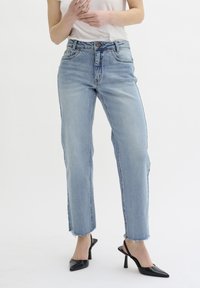 Light blue denim jeans with a straight-leg cut, frayed hem, and five-pocket design, paired with black pointed-toe heels.