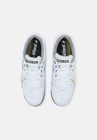 Scarpe da ginnastica bianche con tomaia in pelle liscia, foderate in rete nera e dettagli gialli. Presentano un design testurizzato e lacci tradizionali.