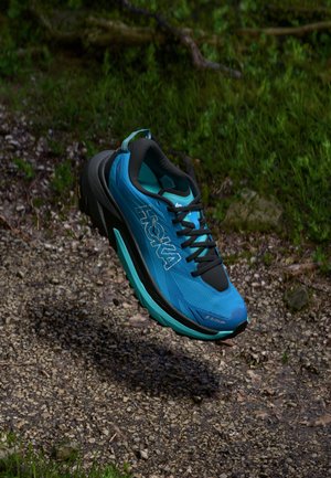 Blaue und schwarze Laufschuhe mit einem strukturierten Mesh-Obermaterial, gepolstertem Kragen und Vibram-Sohle, die ein türkisfarbenes Akzent und ein komplexes Traktionsmuster aufweisen.