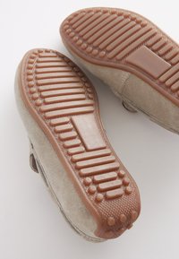 Suede shoes with smooth tan uppers, featuring a rubber sole with textured grooves and raised dots for grip. Lightly worn.