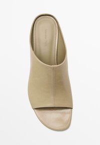 Sandale en cuir beige à enfiler avec un bout ouvert et un dessus courbé. Dispose d'une texture lisse et de détails de couture minimaux. Nom de la marque embossé à l'intérieur.