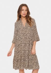 Leopardprint mekko, jossa on V-kaula-aukko, kolmen neljänneksen hihat, kerrostettu helma ja valuva kangas beige ja mustissa sävyissä.