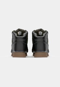 Pantofi de piele negri de înălțime medie, cu guler căptușit, talpă din cauciuc texturat și detalii de cusătură galbenă, expuși din spate.