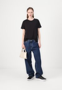 Svart kortermet t-skjorte, løse blå denimjeans, svarte joggesko og en liten beige håndveske med topphåndtak. En enkel, avslappet antrekk.