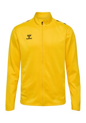 Gul sportjakke med høj krave, fuld lynlås, sidelommer og sort logo; lavet af glat, let vævning med en tætsiddende design.