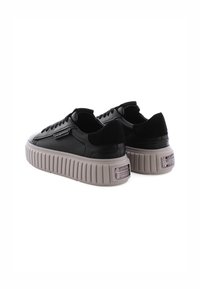 Zwarte leren sneakers met luxe zwarte suede accenten, dikke gestructureerde zool in lichtgrijs, stijlvolle veters en een metallic merkdetail op de hiel.