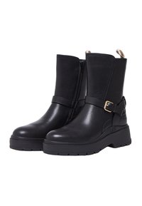 Schwarze Stiefeletten aus Leder mit seitlichem Reißverschluss, einer groben Sohle und einem dekorativen Riemen mit goldener Schnalle. Glatte Textur und elegantes Design.