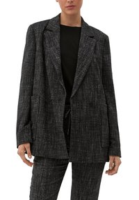 Blazer in tweed nero e grigio con una vestibilità ampia, rever a punta, chiusura a doppio bottone e due tasche frontali. Superficie testurizzata con un motivo sottile.