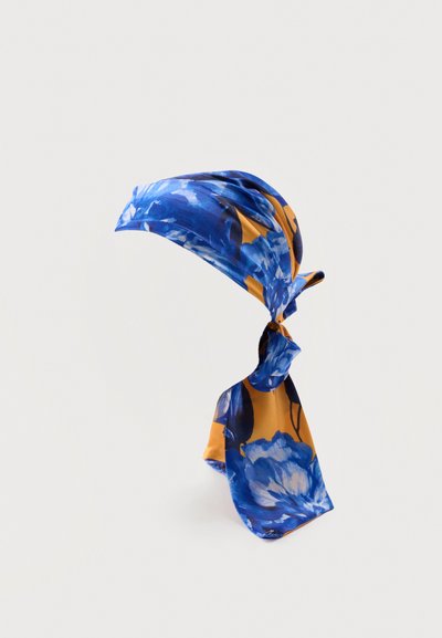 Φουλάρι με μπλε και μουσταρδί κίτρινο λουλουδένιο μοτίβο δεμένο σε κόμπο, απεικονίζεται σε απλό ανοιχτό φόντο.