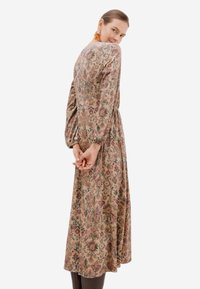 Květinové midi šaty z měkké tkaniny, s dlouhými nabíranými rukávy, přiléhavým pasem a volnou sukní v přírodních tónech.