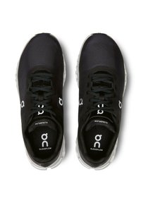 Baskets de course noires avec une tige en maille, des lacets et un logo blanc. Présentent une semelle rembourrée avec une surface texturée et un design minimaliste.