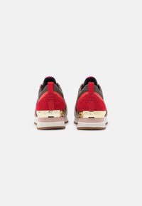 Le sneakers in suede rosso e grigio presentano un accento metallico dorato sul tallone e un'esclusiva linguetta rosa sul retro, con una suola in gomma.