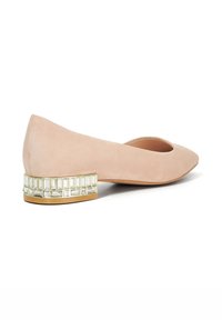Nude suede flat shoe with a rounded toe and a low block heel featuring a geometric crystal accent along the base.