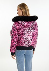Giacca puffer a stampa leopardo rosa con bordo in pelliccia sintetica nera sulla cappuccio, polsini e orlo a coste neri, dotata di tasca laterale.