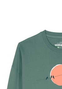 Grüner Baumwollpullover mit rundem Ausschnitt, versehen mit einem pfirsichfarbenen Kreis und zwei Vögeln, die auf einer Linie sitzen, als grafisches Design.