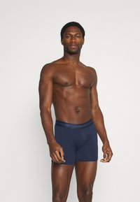 Bóxer de color azul marino con una cinturilla suave que presenta la marca "JBS Underwear", confeccionado en una mezcla de algodón suave y con un diseño ajustado.