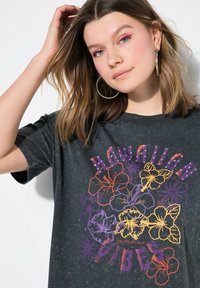 Czarna bawełniana koszulka o luźnym kroju z kolorowym graficznym wzorem w kwiaty w odcieniach pomarańczowego i purpurowego, z napisem "HAWAIIAN VIBES".