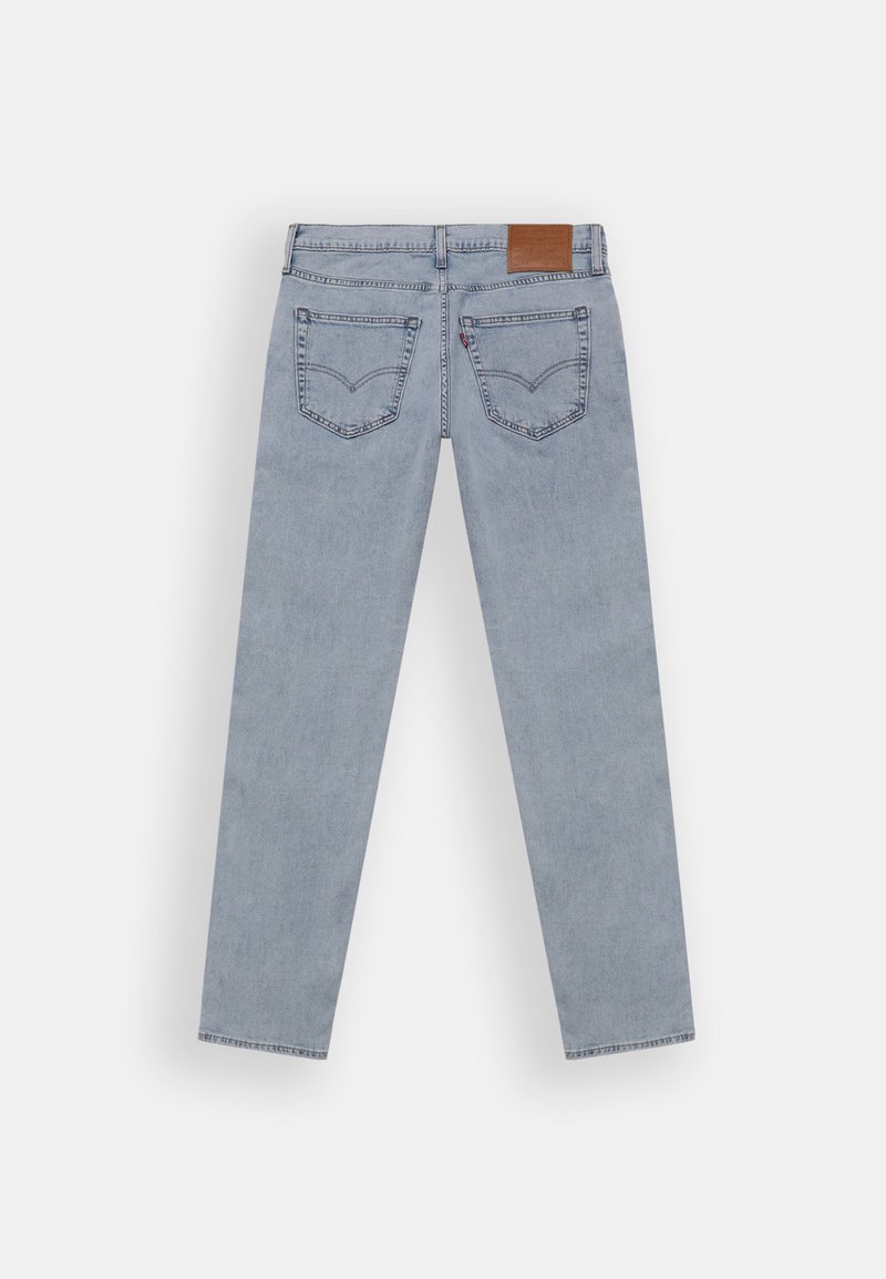 Ljust blå denimjeans med rak bendesign, har två bakfickor och en brun läderlapp vid midjan.