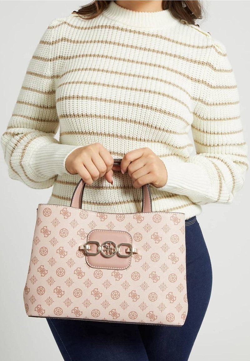 Roze handtas met een patroon en een gladde structuur, voorzien van een opvallende sluiting en dubbele handvaten, vastgehouden voor een persoon die een gestreepte trui draagt.