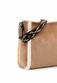 Borsa in suede marrone con bordo bianco peloso, dotata di una tracolla regolabile con motivo. Logo distintivo visibile sul fronte. Forma rettangolare.