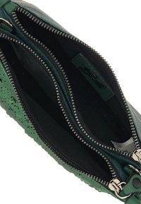 Borsa di pelle verde con due scomparti con zip, caratterizzata da perforazioni testurizzate all'esterno e una fodera nera liscia all'interno.