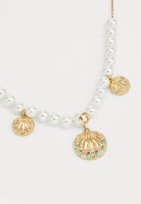 Perlenkette mit goldenen Muschel-Anhängern, akzentuiert mit Türkis und Kristalldetails, die mit einem glänzenden, strukturierten Finish aufwartet.