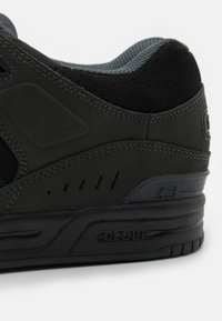 Sort sneakers med en glat ruskindsoverdel, perforerede detaljer, polstret krave og en struktureret gummisål med brandingdetaljer.