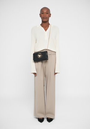 White ribbed long-sleeve shirt, beige high-waisted trousers, black crossbody bag with gold hardware, and pointed black heels.