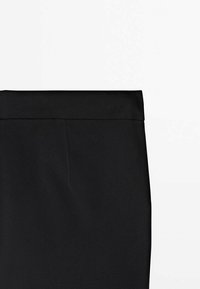 Zone de la taille d'une jupe noire, montrant la ceinture et la texture supérieure du tissu avec une finition propre et lisse sur un fond blanc.