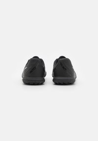 Scarpe da ginnastica nere con una superficie testurizzata, tallone rinforzato e suola in gomma. Presentano un marchio sui lati e un collarino aderente.