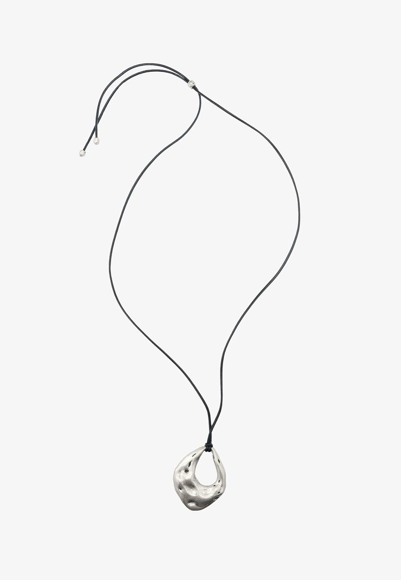 Ciondolo in argento metallico con una forma organica e texturizzata, sospeso a un cordino nero. Lunghezza regolabile con piccoli dettagli in argento.