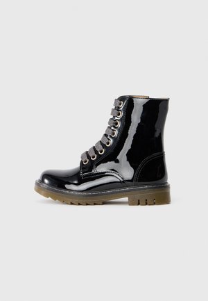 Bottines en cuir verni noir avec un bout arrondi, cinq œillets en métal et des lacets gris. Elles présentent une semelle en caoutchouc texturé avec un motif à crampons.