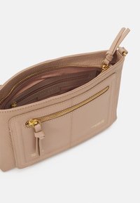 Borsa in pelle beige con cerniere dorate, caratterizzata da una texture liscia e molteplici scomparti, inclusa una tasca esterna con zip.