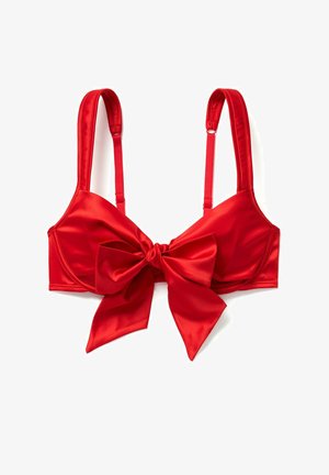 Red satin bra with adjustable straps and a large bow detail at the front. Smooth texture, structured cup design, and vibrant color.
