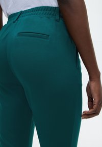 Τιρκουάζ, ελαφριά παντελόνια με ελαστική μέση και κομψή εφαρμογή. Διαθέτουν πίσω τσέπη χωρίς ορατά κλεισίματα.