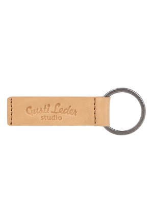 Hellbrauner Leder-Schlüsselanhänger mit Nähten an beiden Enden und einem Metallring auf einer Seite, geprägt mit dem Text „"Gusti Leder studio"".