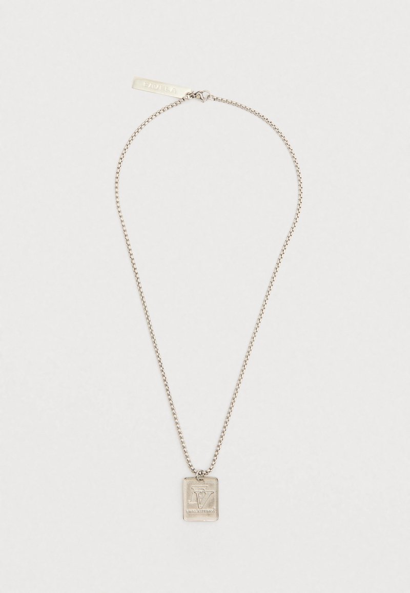 Ezüst lánc nyaklánc téglalap alakú medállal, amelybe a "FAVELA STUDIOS" logó van gravírozva, és a kapocshoz közeli, gravírozott címke illeszkedik, fehér háttéren.