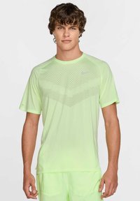 Limegrøn atletisk t-shirt med et tekstureret mønster foran. Korte ærmer, rund halsudskæring og et lille logo på brystet.