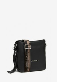Sort crossbody taske lavet af syntetisk materiale med flad form, der har et logo strap i brun og en frynse detalje.