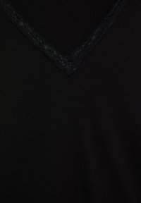 Fekete felső, V-nyakkivágással és finom fekete csipke díszítéssel. Az anyag simának és puhának tűnik, egységes textúrával.