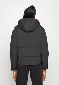 Black puffer jacket with a hood, featuring a quilted design, elastic cuffs, and a cropped fit. Smooth texture with no visible patterns.