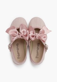 Jasnoróżowe buty typu Mary Jane z teksturowanym materiałem cholewki, satynowymi kokardkami i regulowanym paskiem. Wkładka wewnętrzna zawiera logo "Pisamonas".