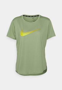Ljusgrön Nike Dri-FIT T-shirt med korta ärmar och en stor gul Nike-swoosh logga i mitten på framsidan.